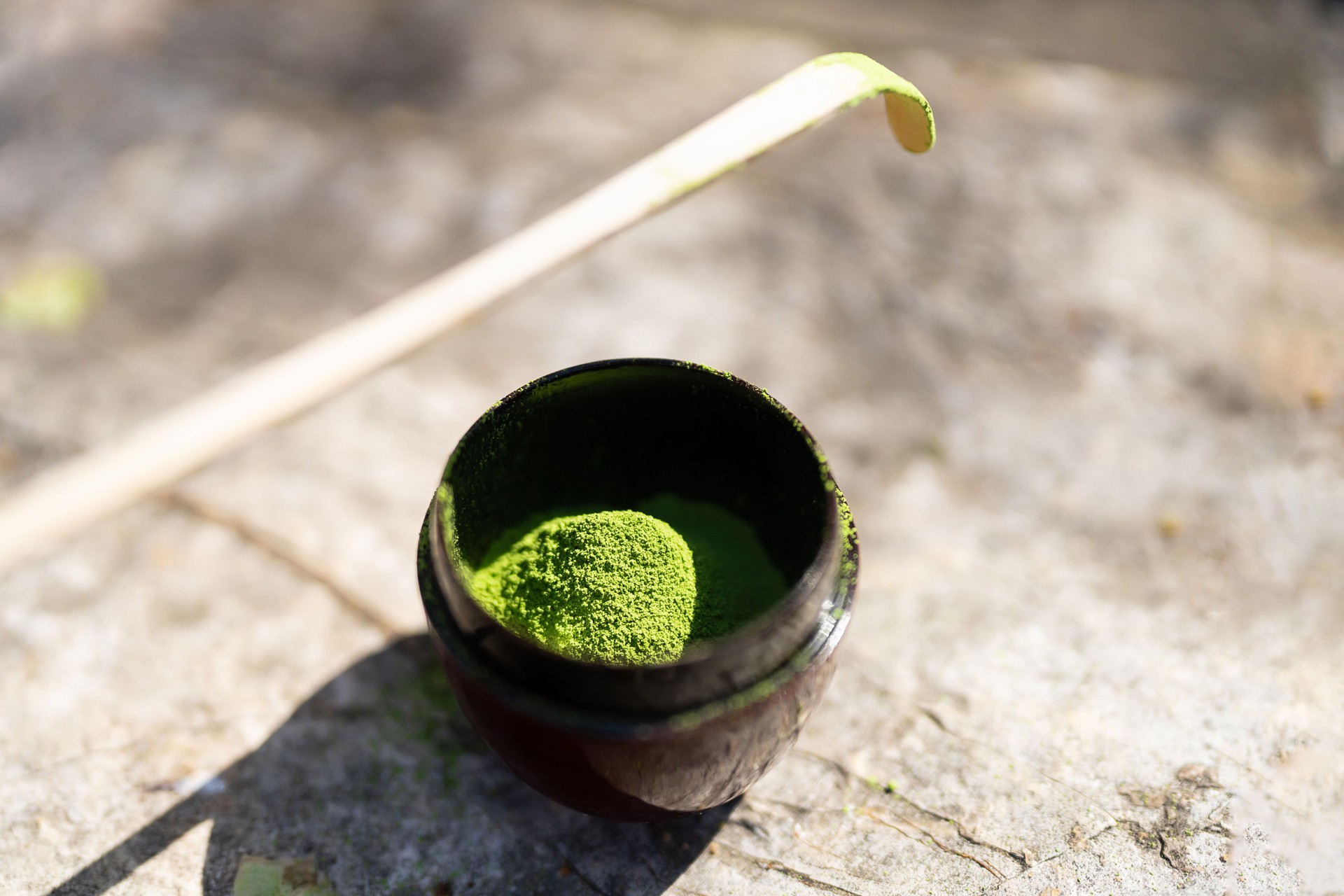 Matcha tea powder in a bowl and bamboo matcha spoon